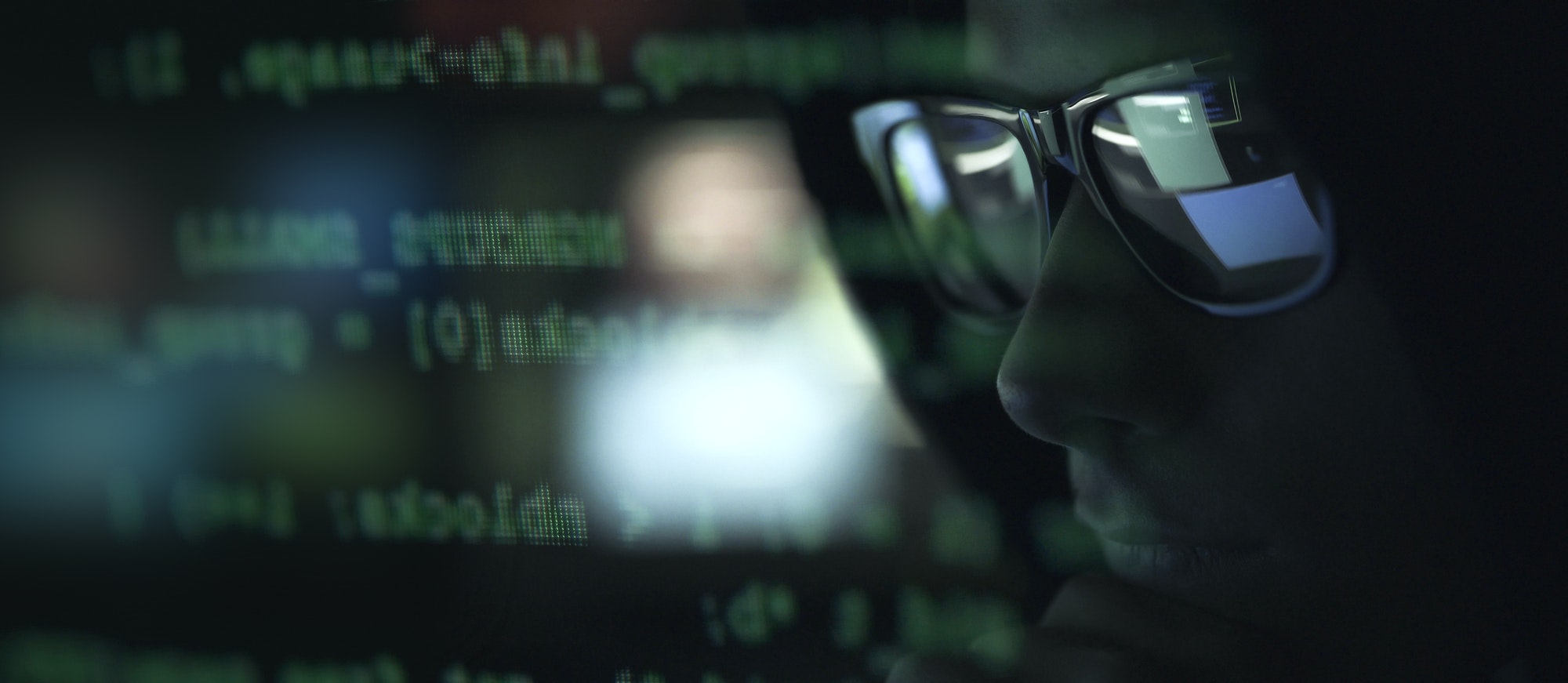 Hacker with sunglasses and code on the screen